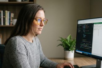 Femme portant des lunettes anti-lumière bleue devant un écran d'ordinateur portable dans un bureau à domicile moderne