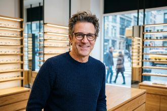 Homme d'âge moyen souriant dans une boutique d'optique moderne